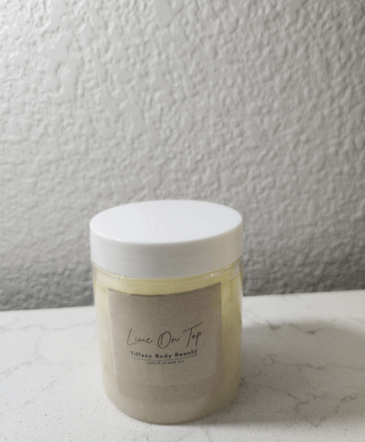 Lime On Top Body Buffer jar with a white lid on a marble surface, designed for moisturizing skin.